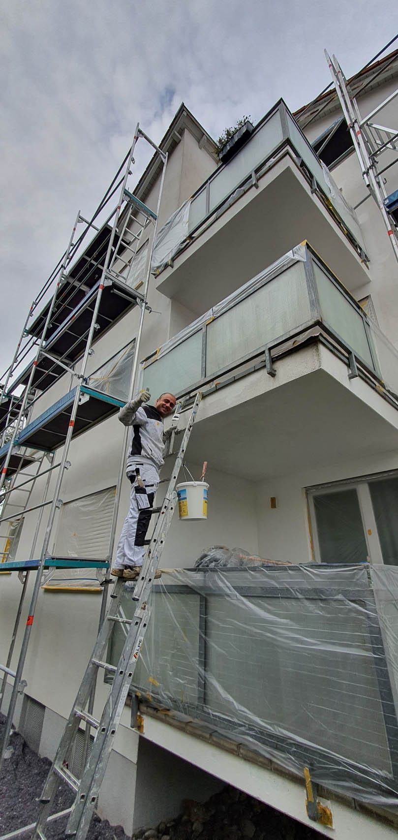 Maler arbeitet an einem Balkon mit Gerüst.