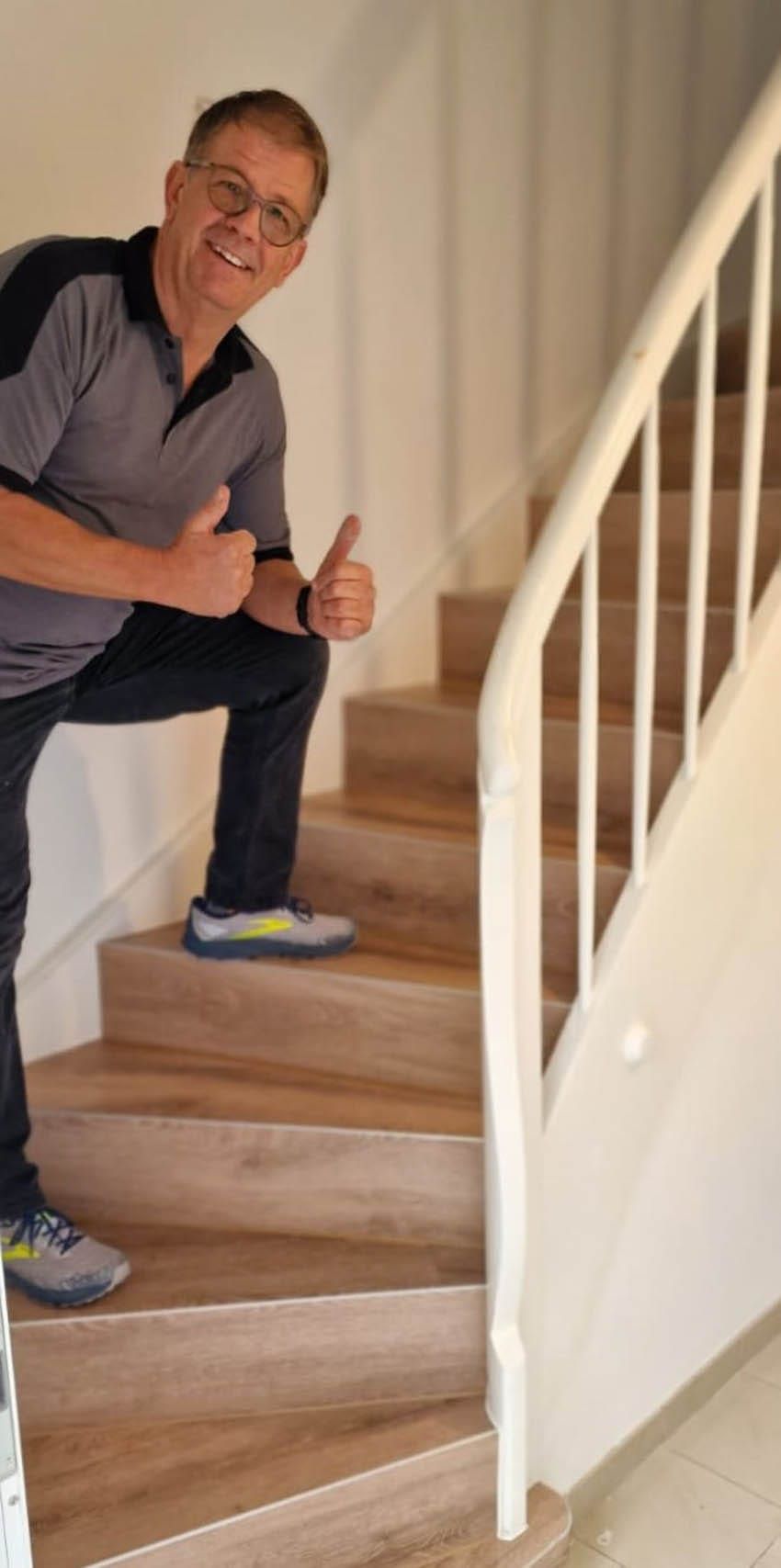 Mann gibt Daumen hoch auf einer Treppe.