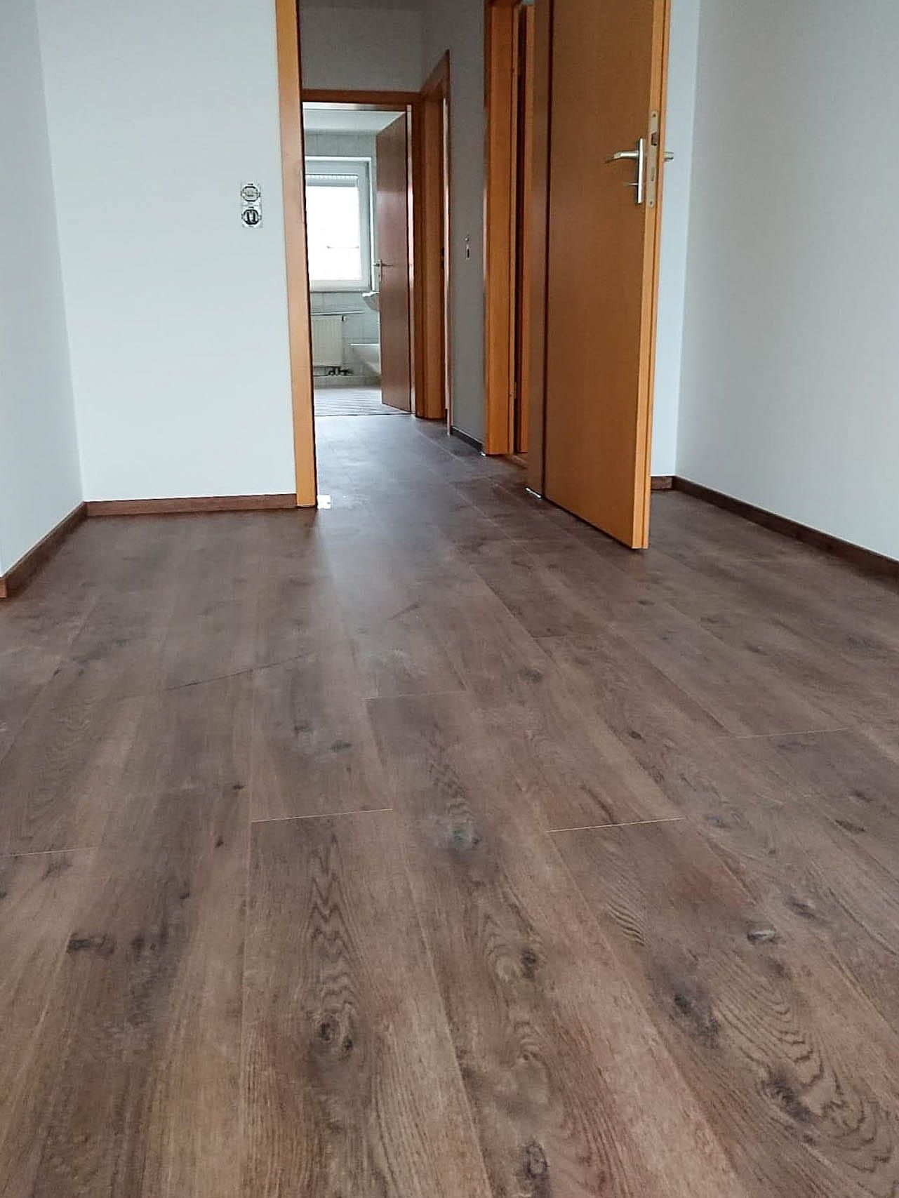Modernes Zimmer mit Holzboden und offenen Türen.