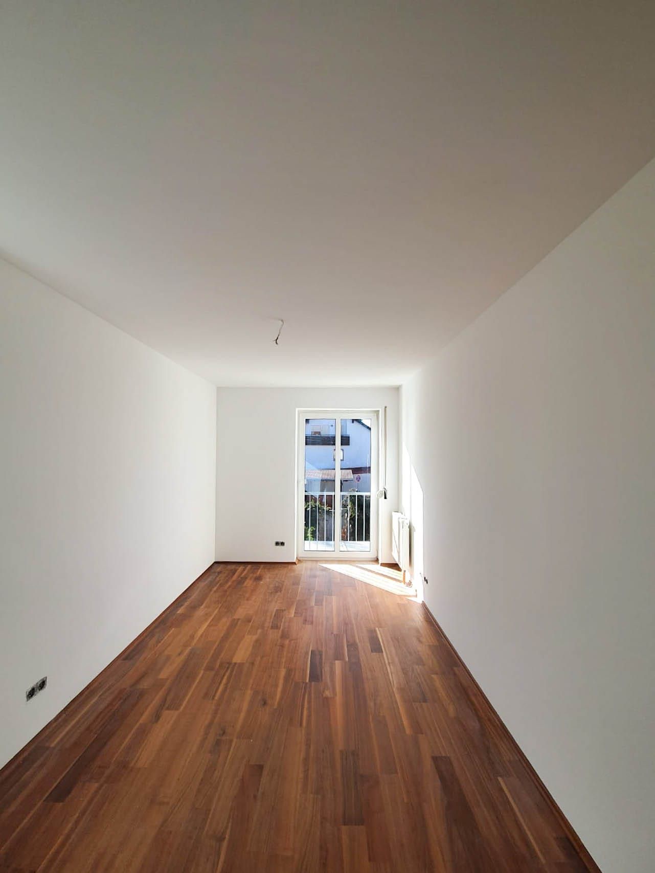 Helles Zimmer mit Holzboden und Balkonfenster