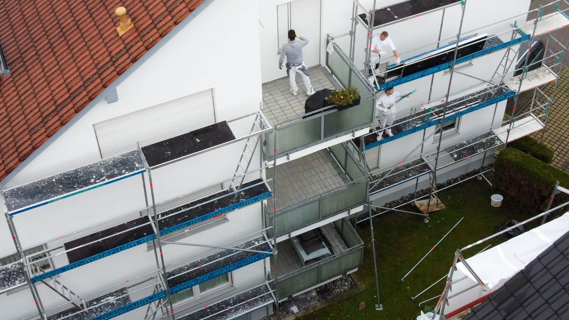Arbeiter am Gerüst beim Malen eines Gebäudes