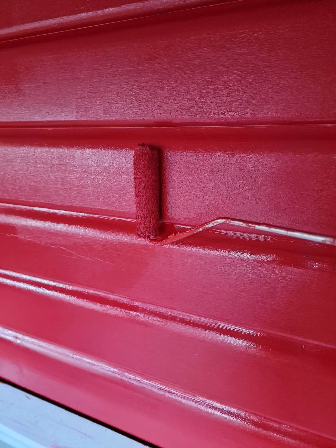 Roter Anstrich mit Farbroller auf Oberfläche