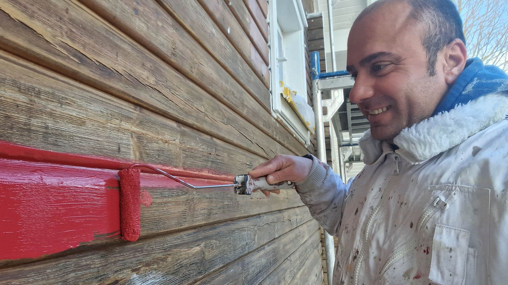 Mann streicht eine Wand in roter Farbe
