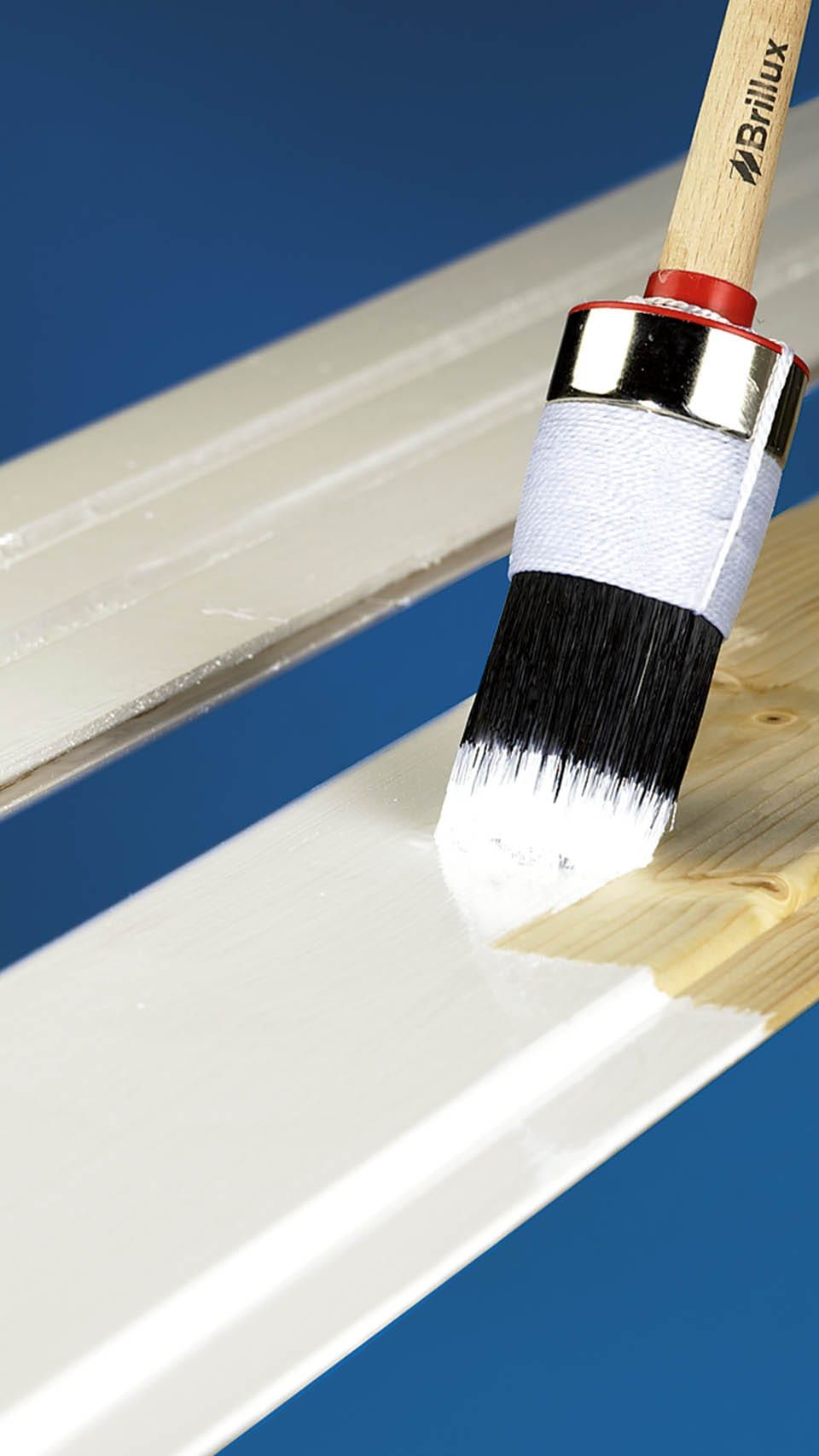 Pinsel streicht weiße Farbe auf Holzoberfläche.