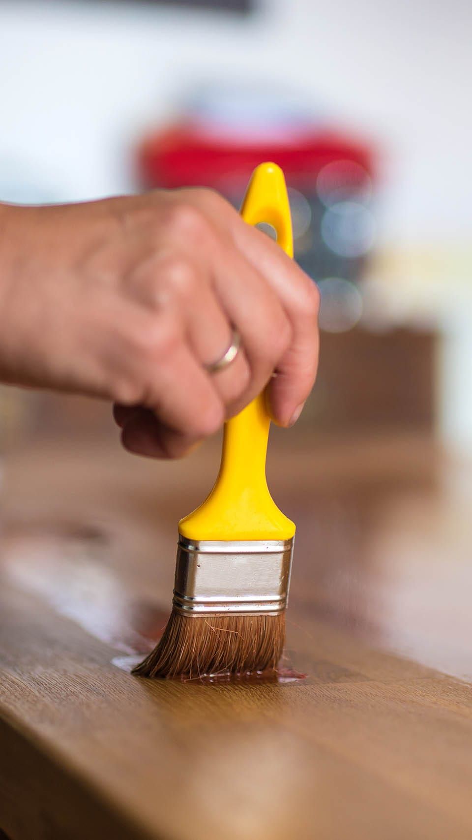 Hand mit Pinsel auf Holzoberfläche