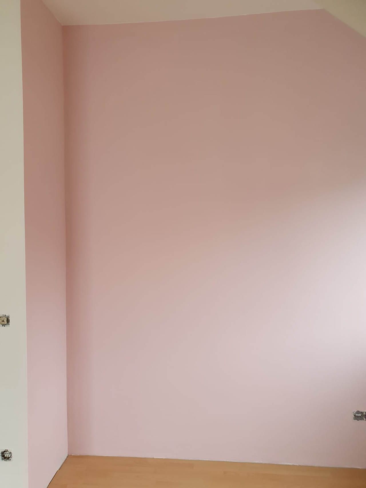 Rosa Wand in einem Innenraum mit Holzfußboden
