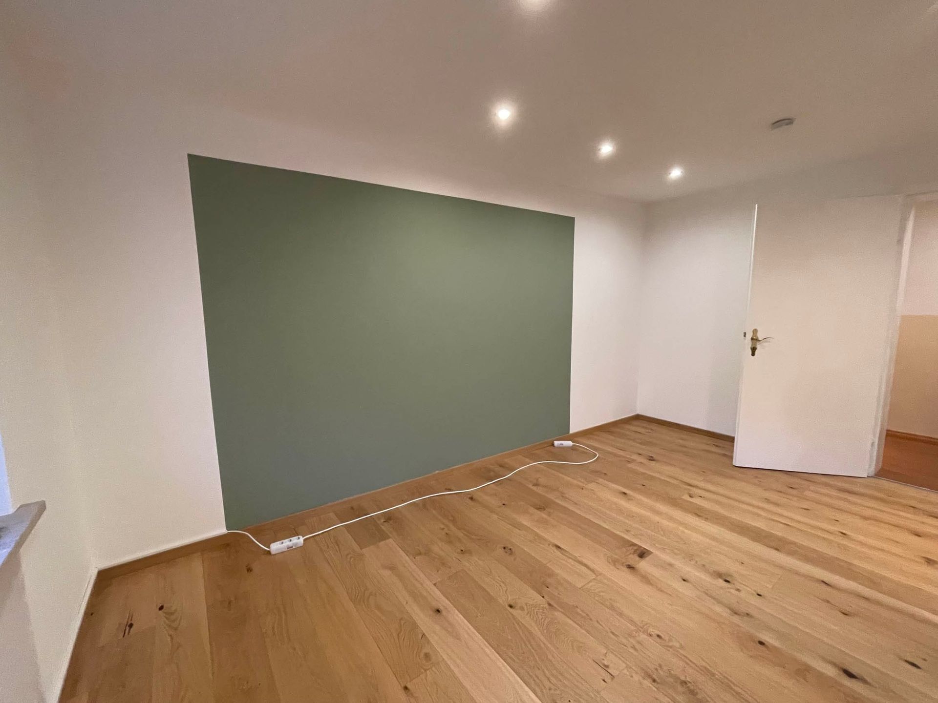Heller Raum mit grünem Akzentwand und Holzfußboden