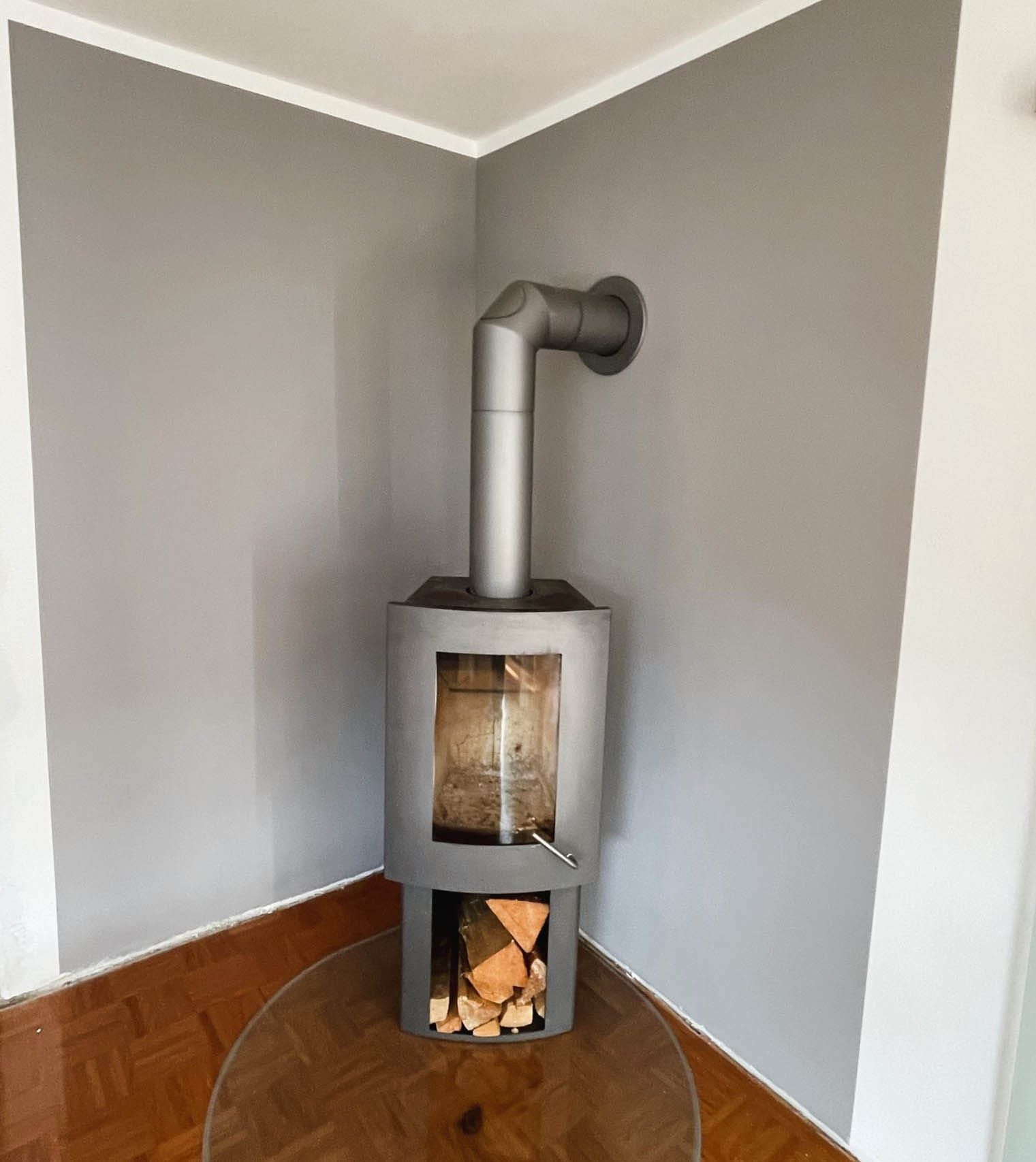 Moderner Ofen in grauem Raum mit Holz