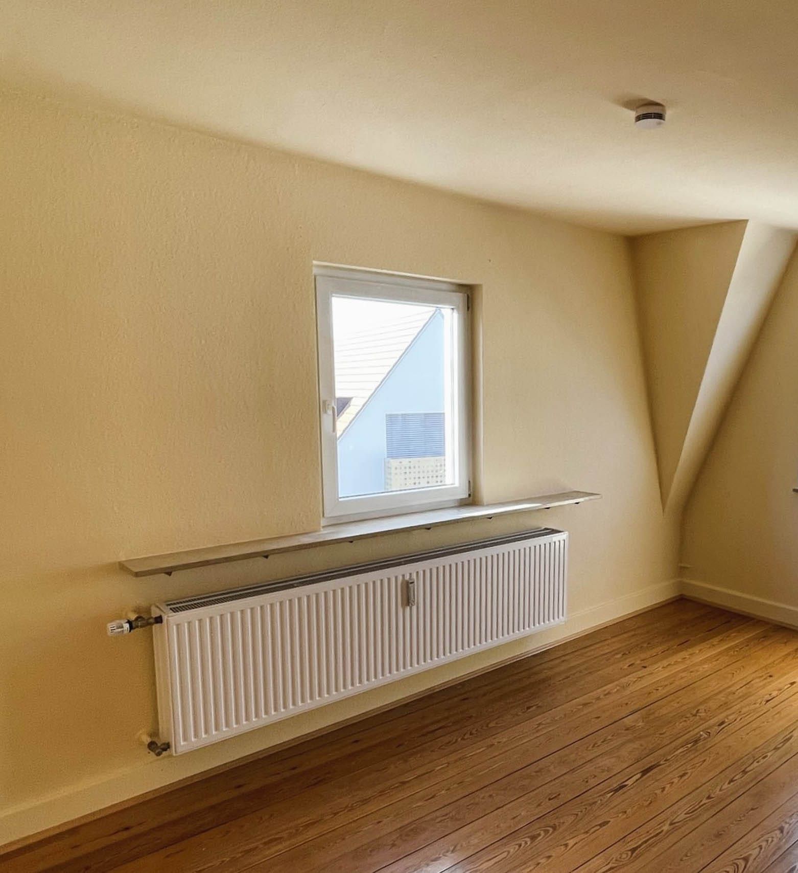 Heller Raum mit Fenster und Heizkörper.