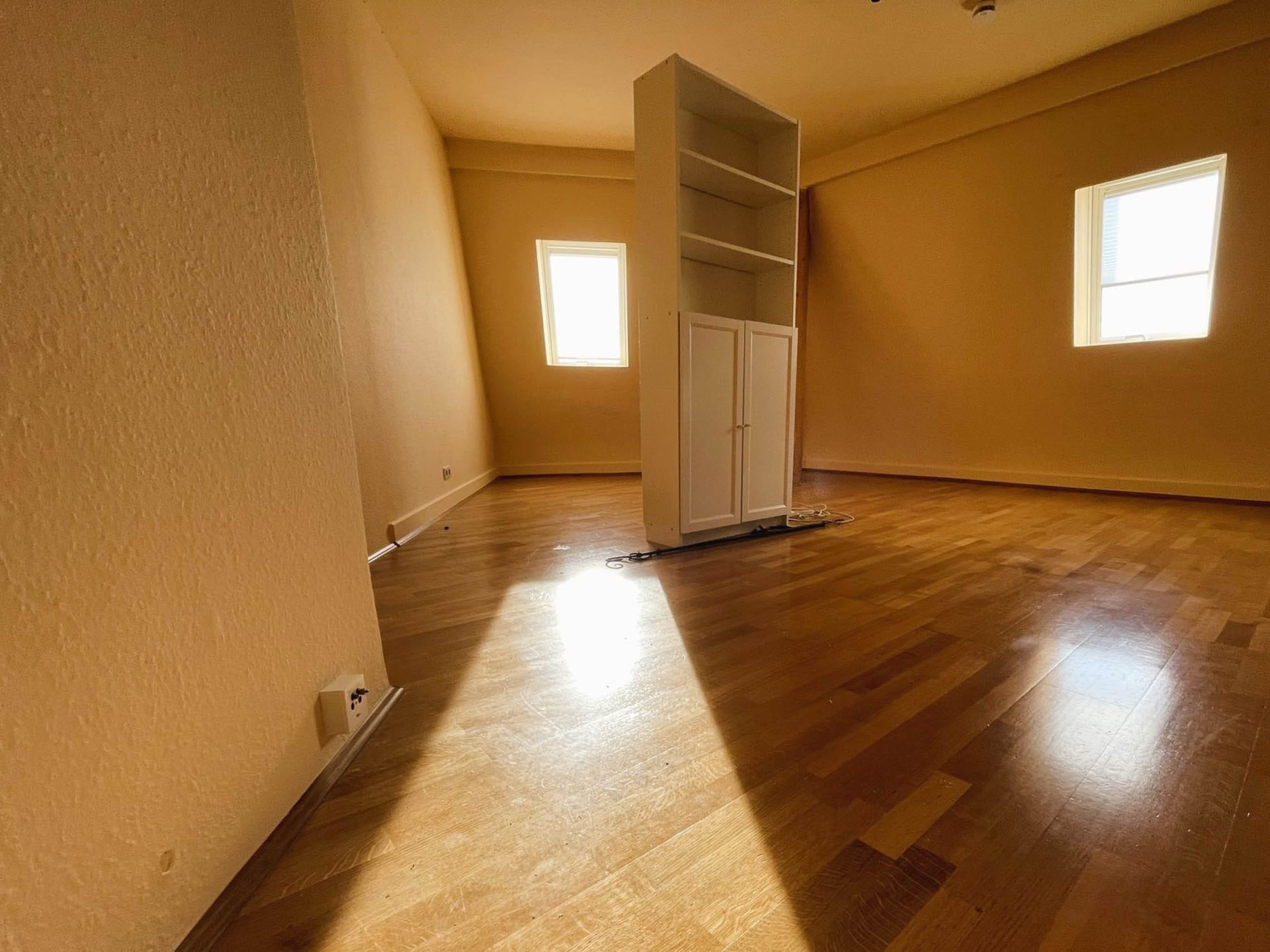 Helles Zimmer mit Holzfußboden und Fenster.