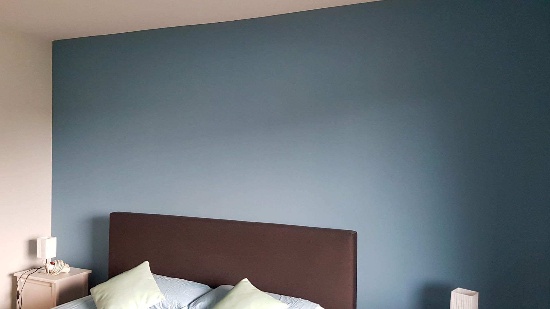Schlafzimmer mit blauer Wand und Bett.