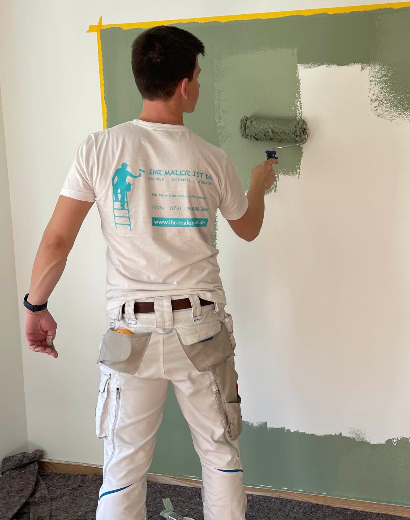 Maler beim Streichen einer grünen Wand.