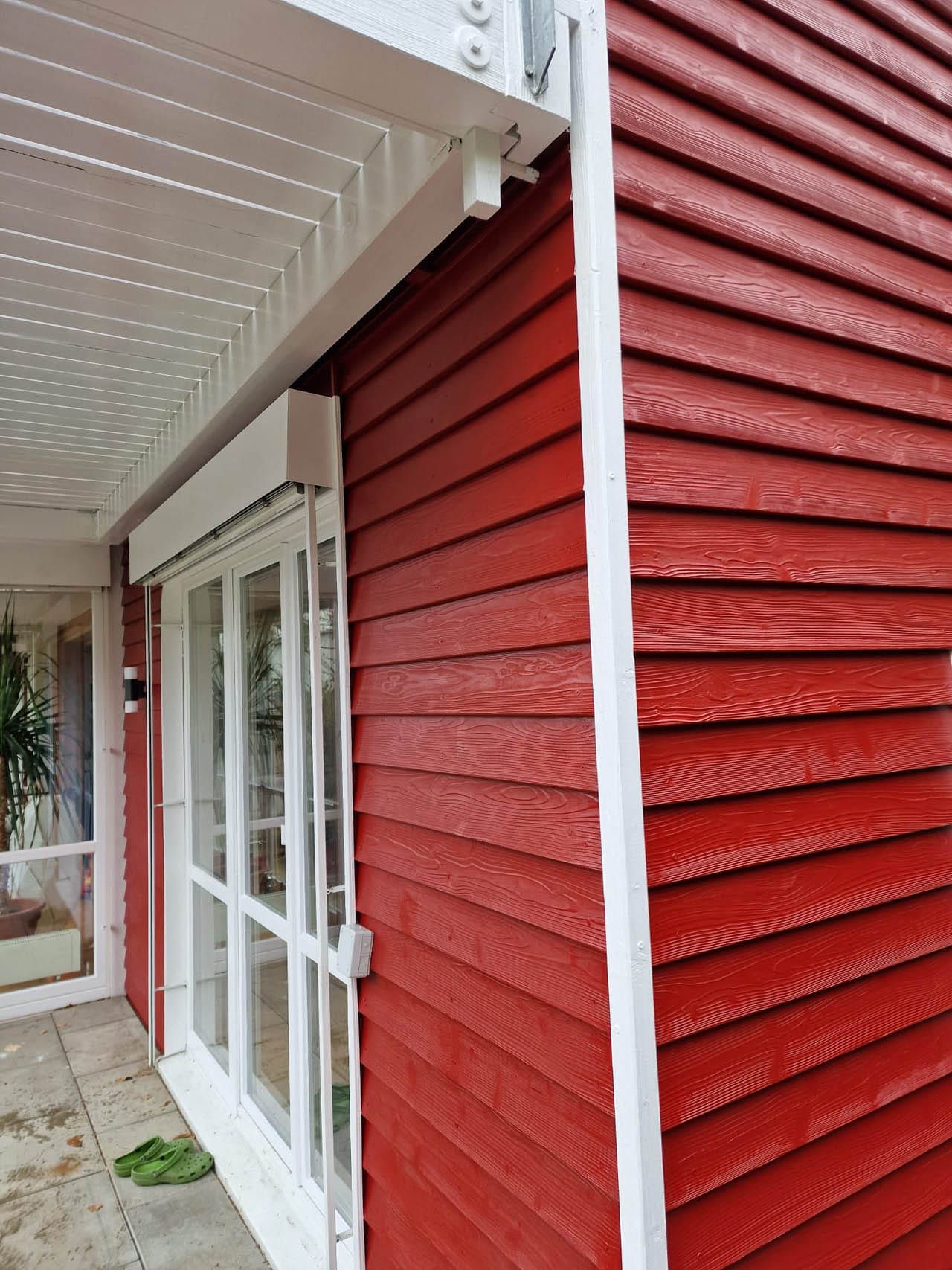 Helle rote Holzwand mit Fenster und Überdachung