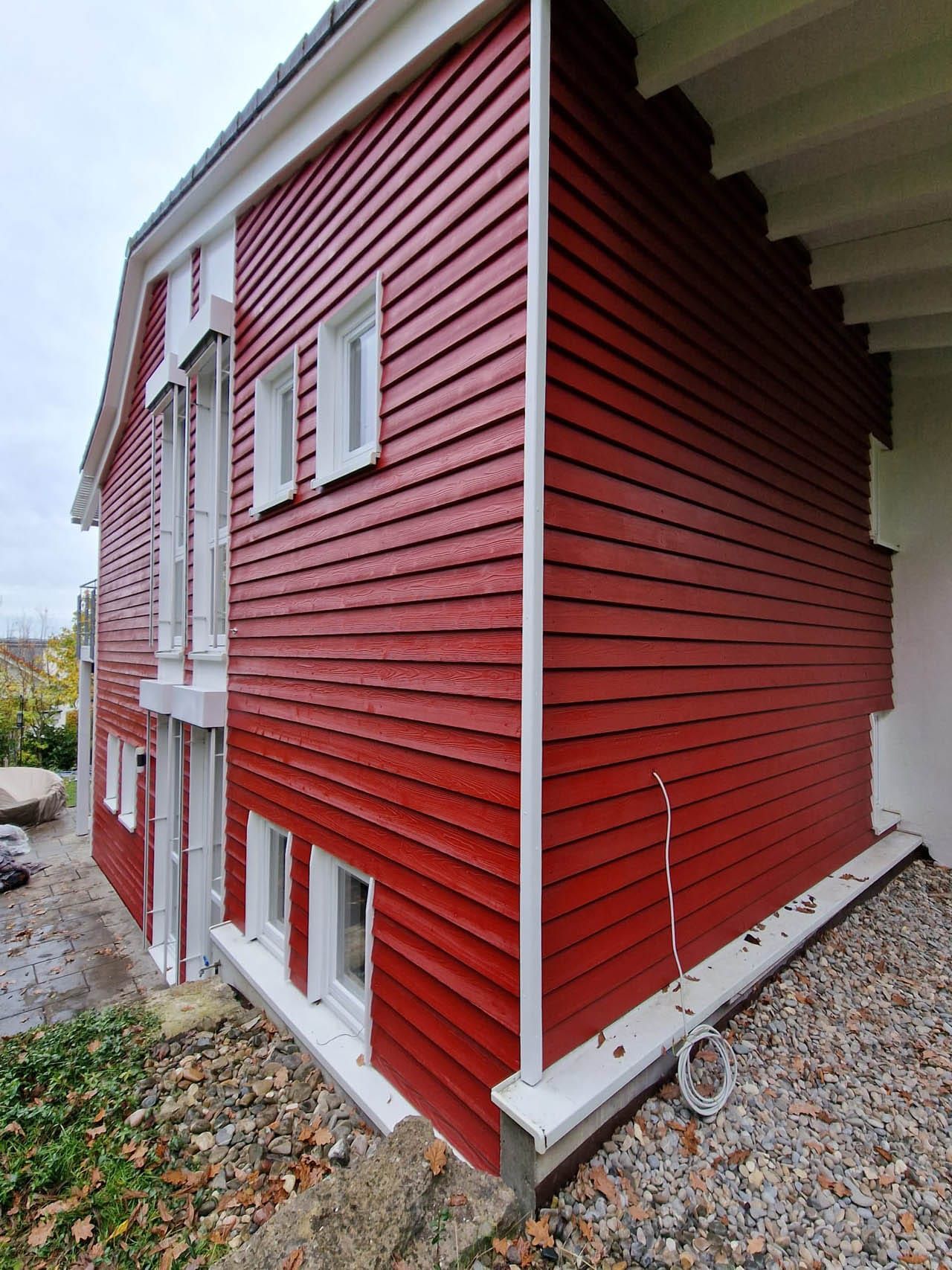 Nachher: Modernes rotes Holzhaus mit Fenstern