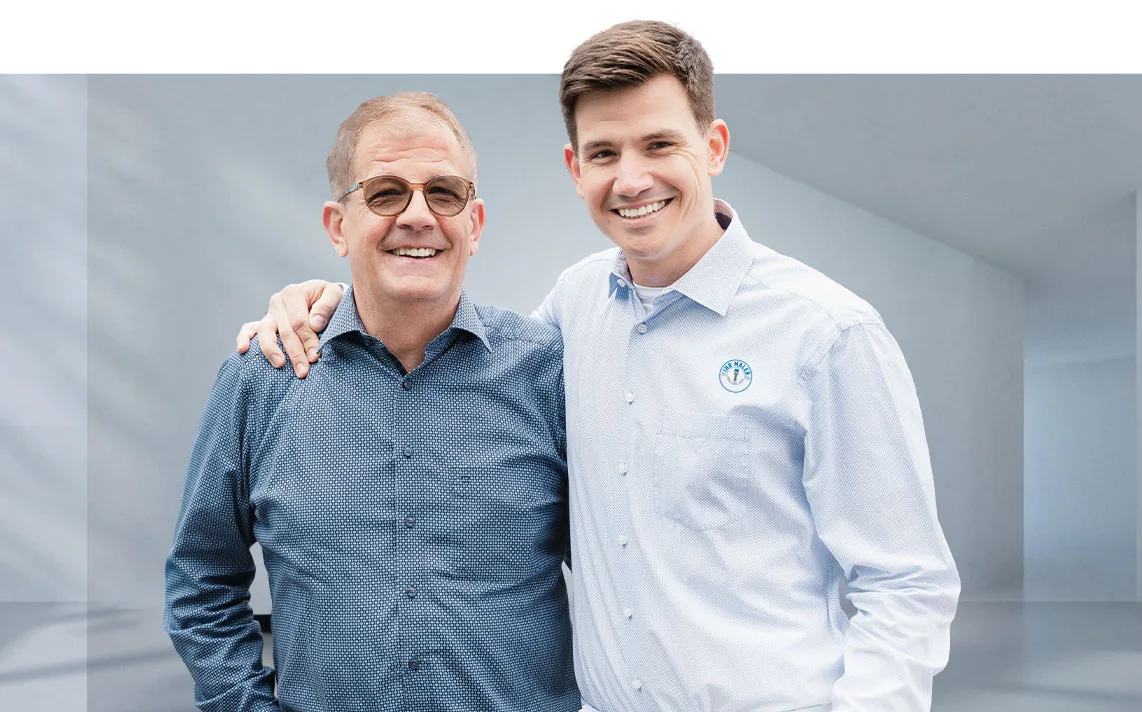 Zwei Männer, Frank und Marcel Niebeling, lächeln und posieren freundlich zusammen.