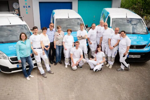 Teamfoto eines Malerbetriebs vor ihren Fahrzeugen